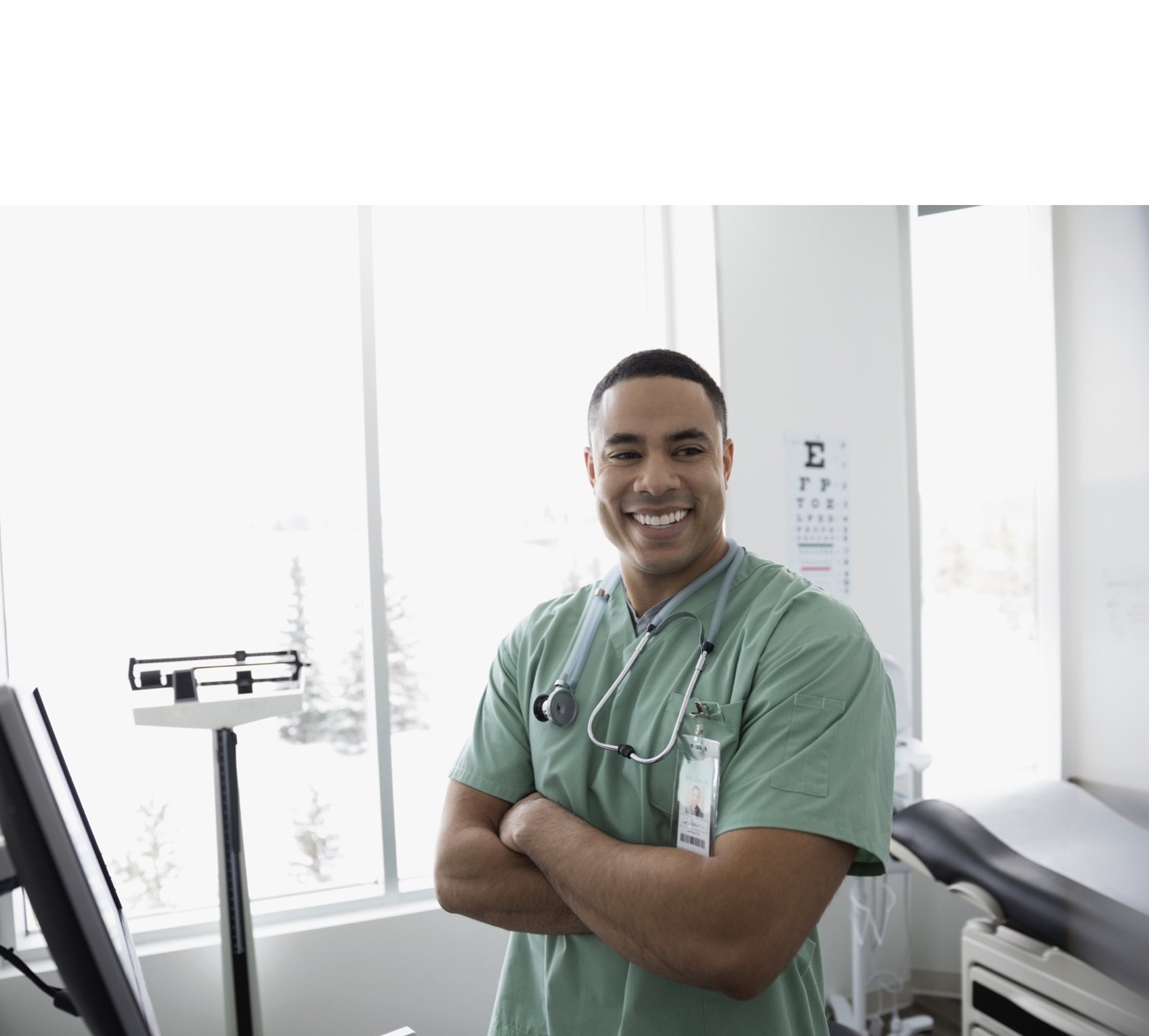 Male nurse with arms crossed in clinic examination room