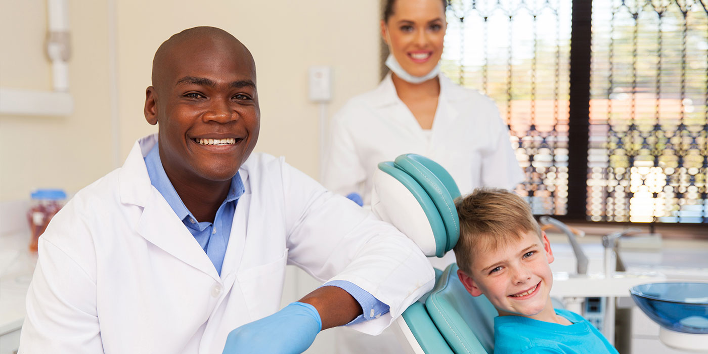 Clinical Dental Assistant smiling with dentist and child patient