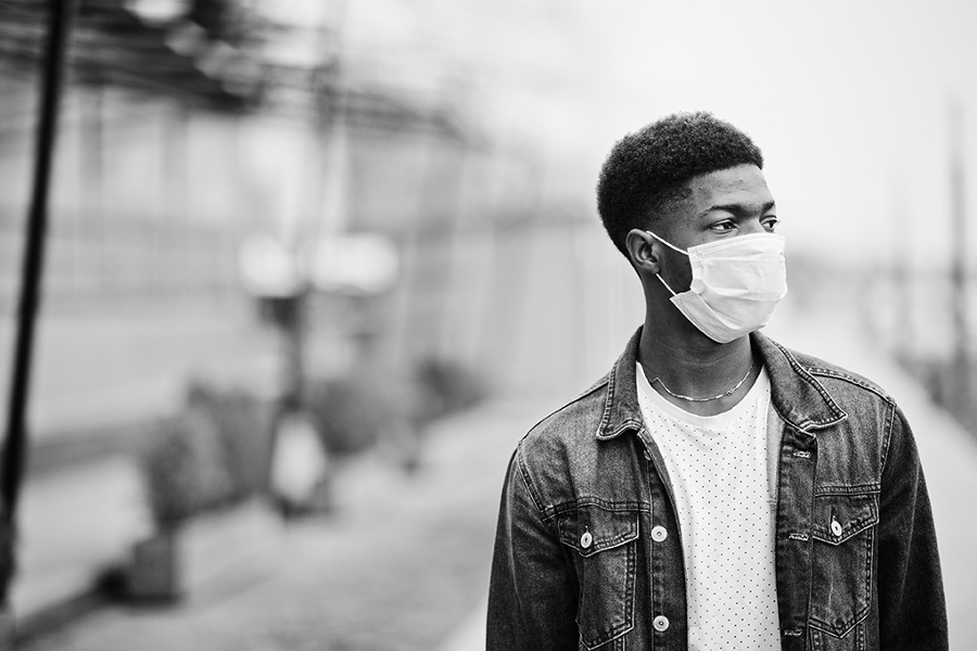Young black male with a mask standing outdoors