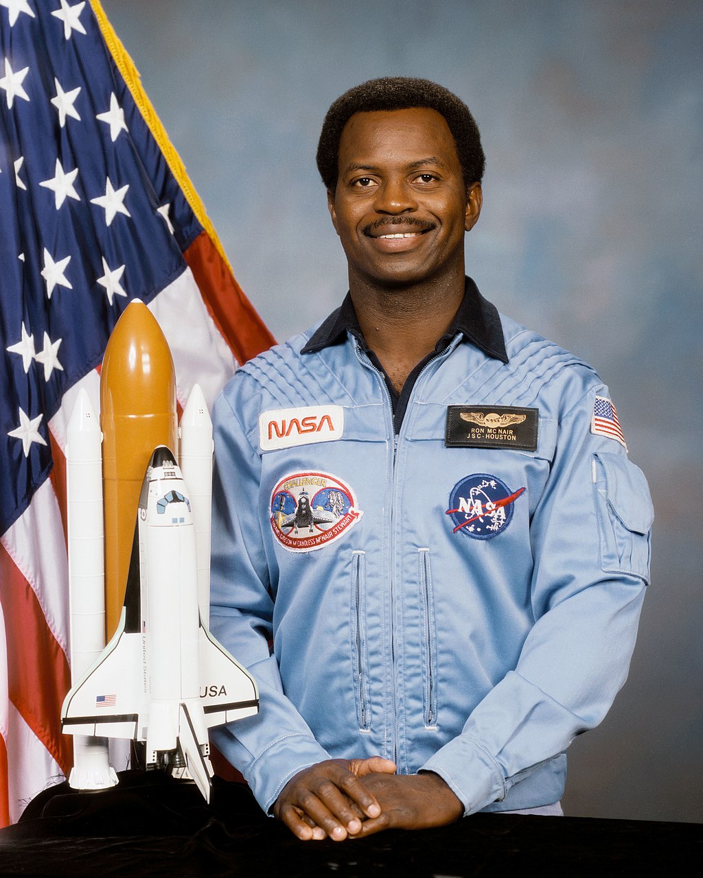 Photo of Ronald Erwin McNair standing next to a model space shuttle