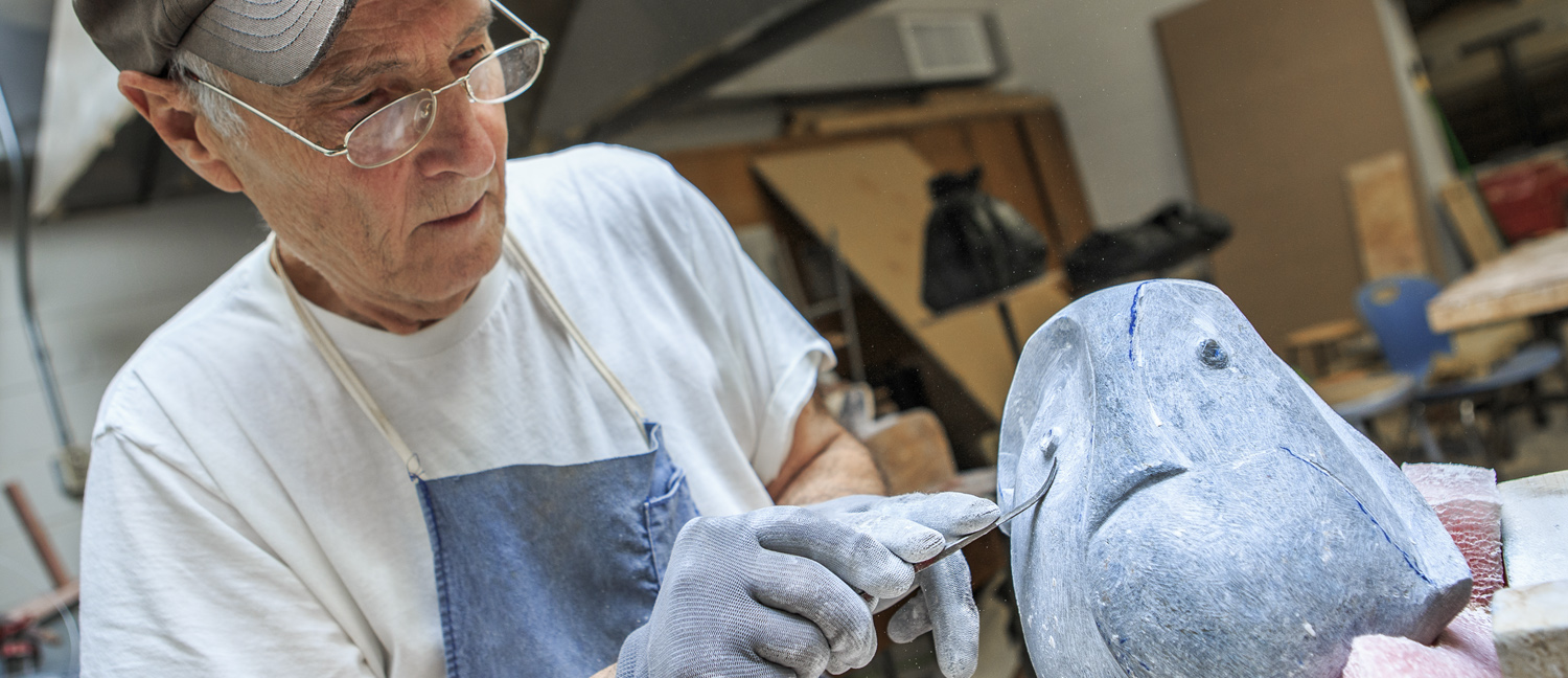White male senior citizen carving a scultpture