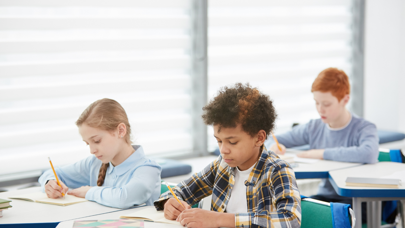 Child writing on paper with teacher looking over shoulder.