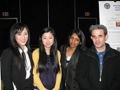 3 females and 1 male student posing in front of presentation poster