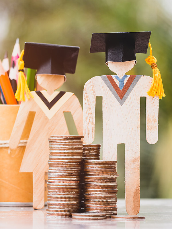 wooden figurines wearing graduation caps and pile of change in front of them