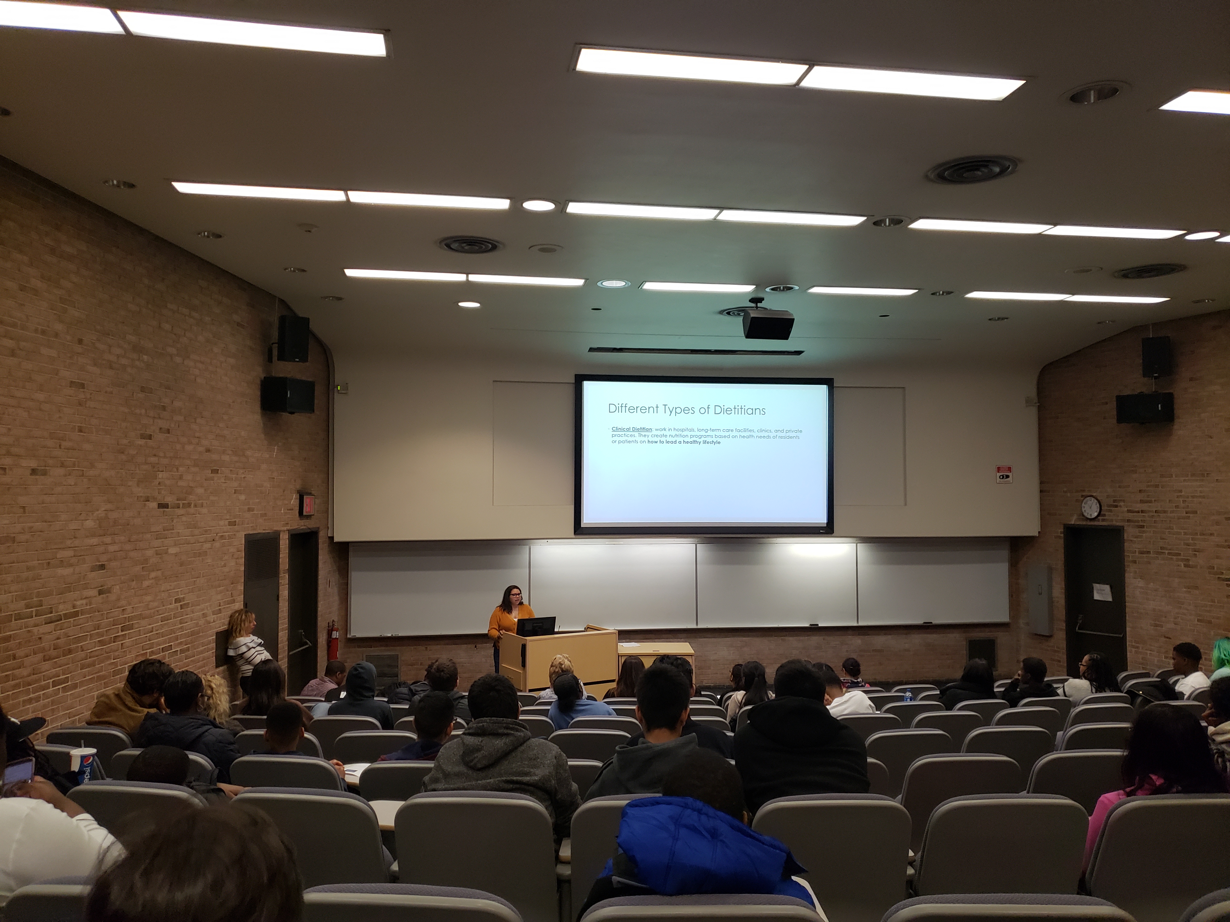 presenter speaking in front of students in auditorium