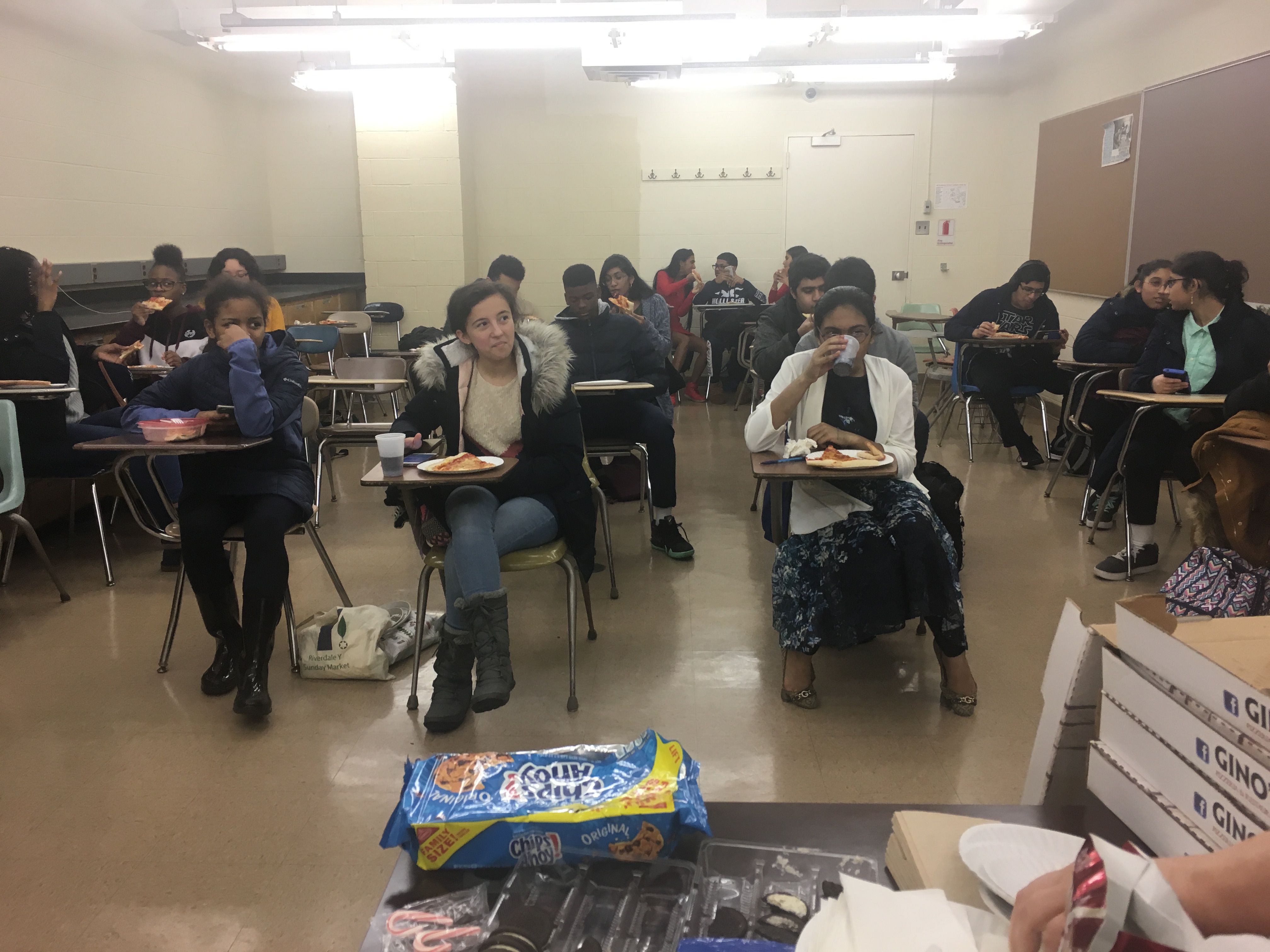 students in classroom at their desks, enjoying pizza party