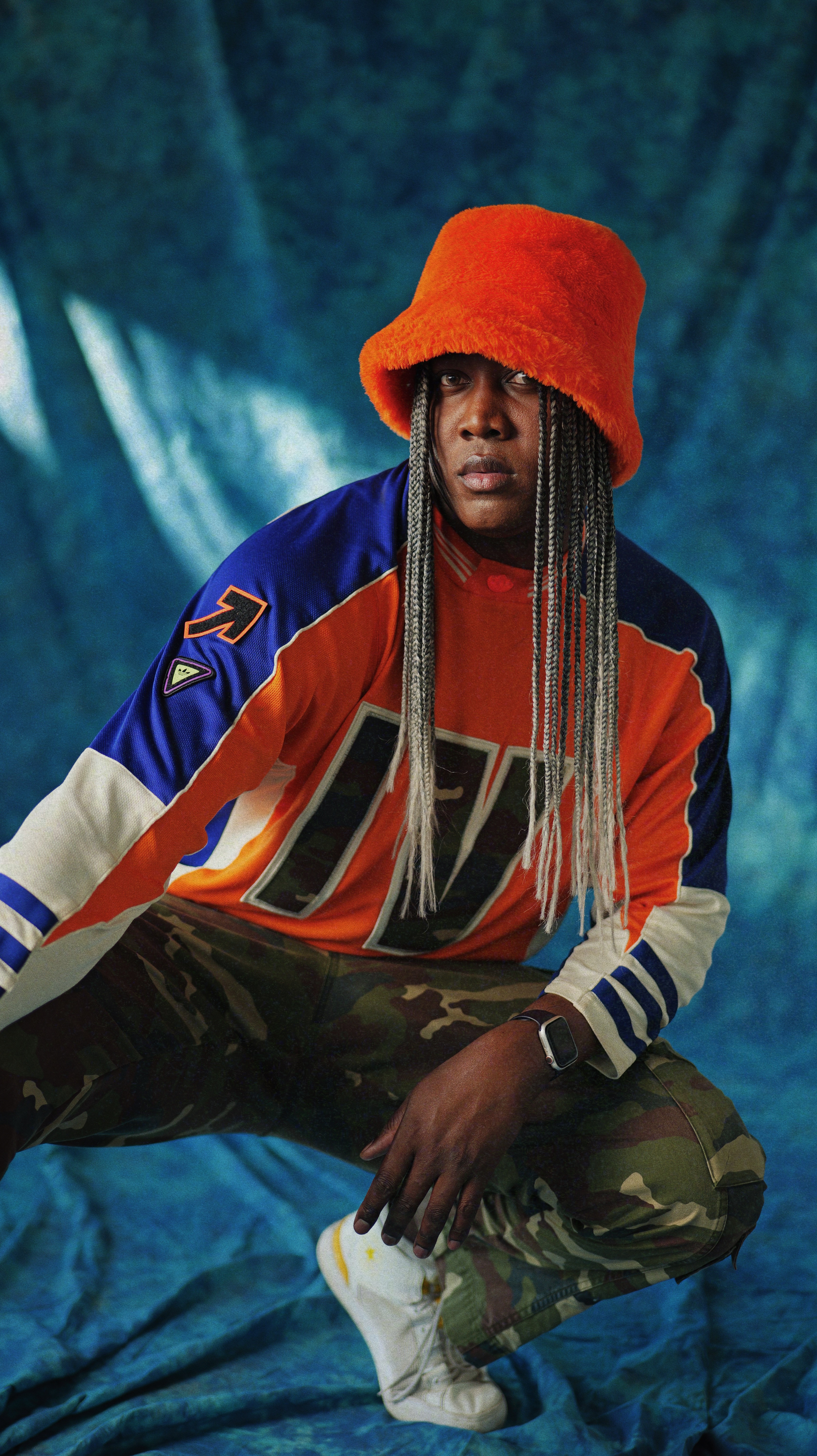 Simeon Pollydore wearing a red hat and camo pants and long braids
