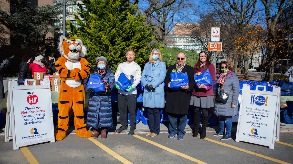 President Mangino and the team and mascot standing holding pantry bags