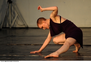 Professor Emily Berry wearing a black dress, crouched on the ground with one hand raised