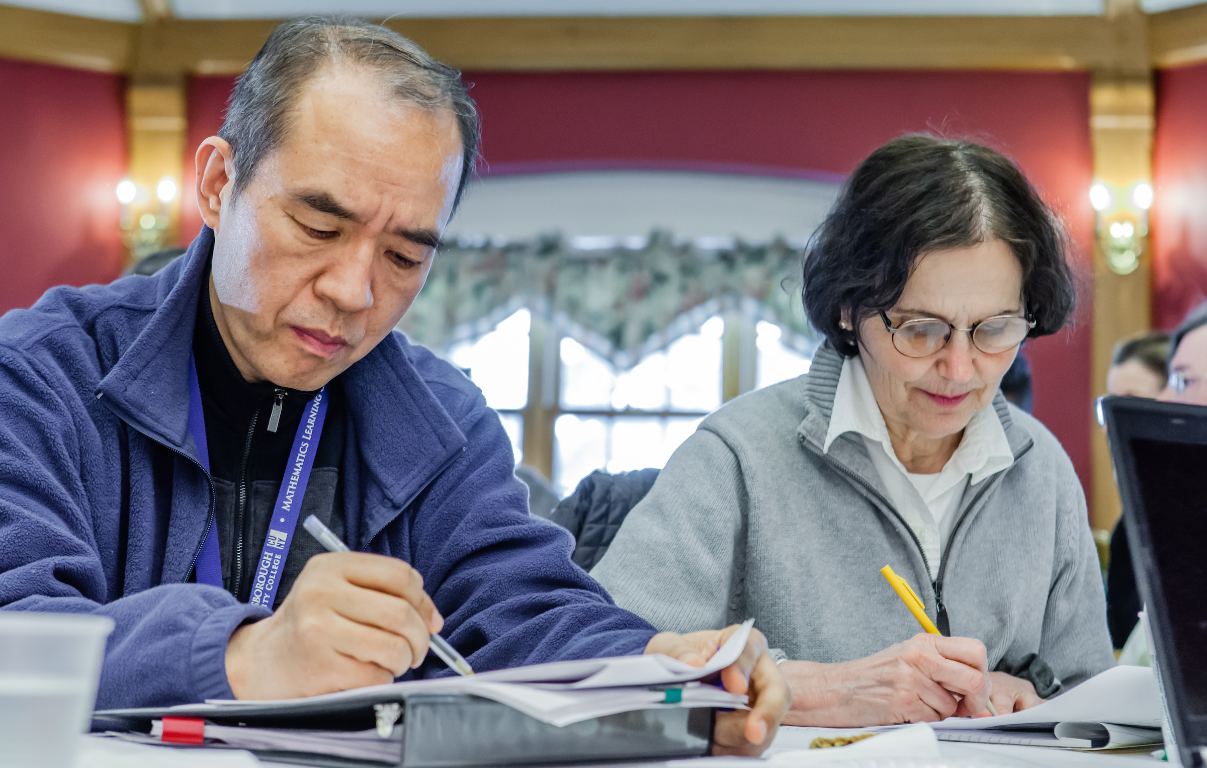 male and female faculty members writing on papers