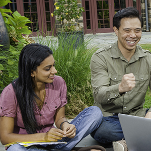 two students sitting down and working together